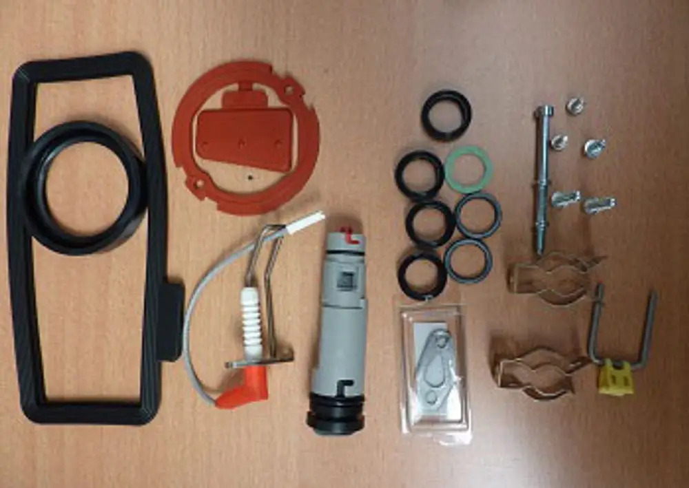 Ersatzteile für Remeha-Produkte, bestehend aus verschiedenen Dichtungen, Ringen, Schrauben und Halterungen, angeordnet auf einem Holzuntergrund.